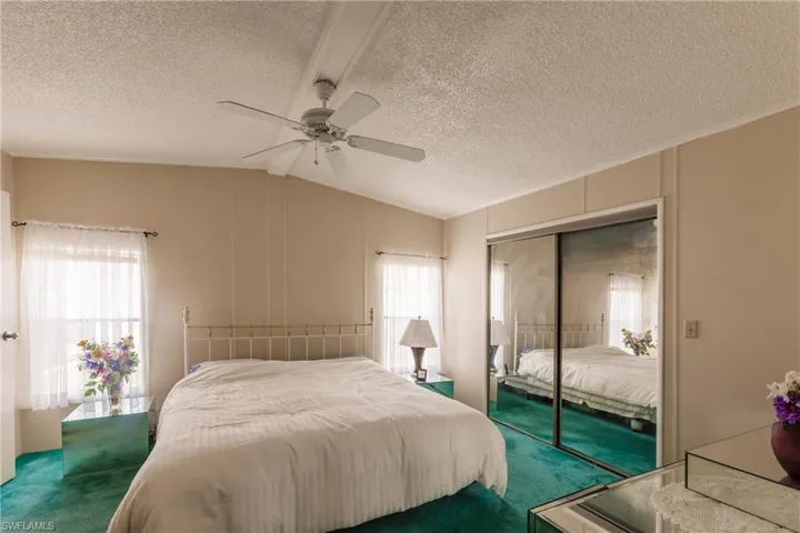 Bedroom featuring a closet, ceiling fan, lofted ceiling, and multiple windows