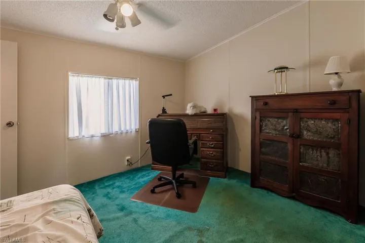 Carpeted office space featuring ornamental molding, a textured ceiling, and ceiling fan