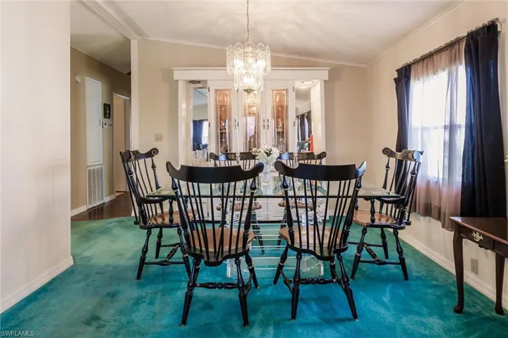 Carpeted dining room with crown molding, a notable chandelier, and vaulted ceiling