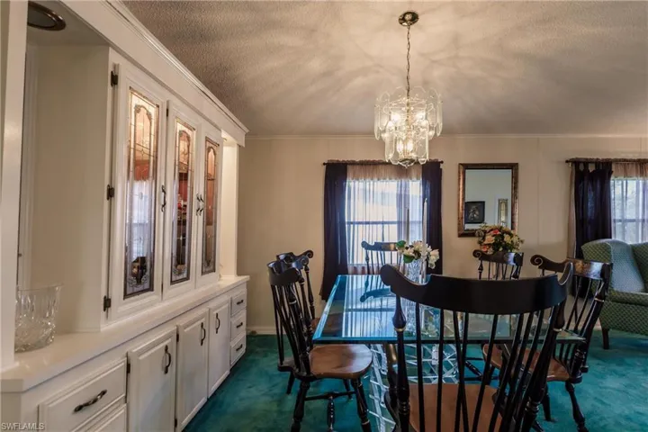 Carpeted dining room featuring ornamental molding, a chandelier, and a textured ceiling
