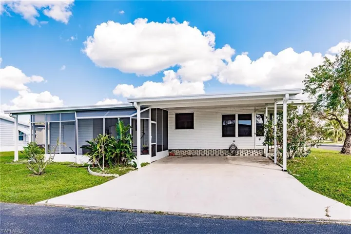 View of front of home featuring a sunroom, a front lawn, and a carport