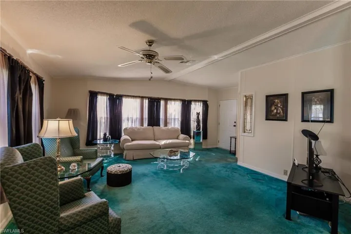 Carpeted living room with ceiling fan, a textured ceiling, and lofted ceiling