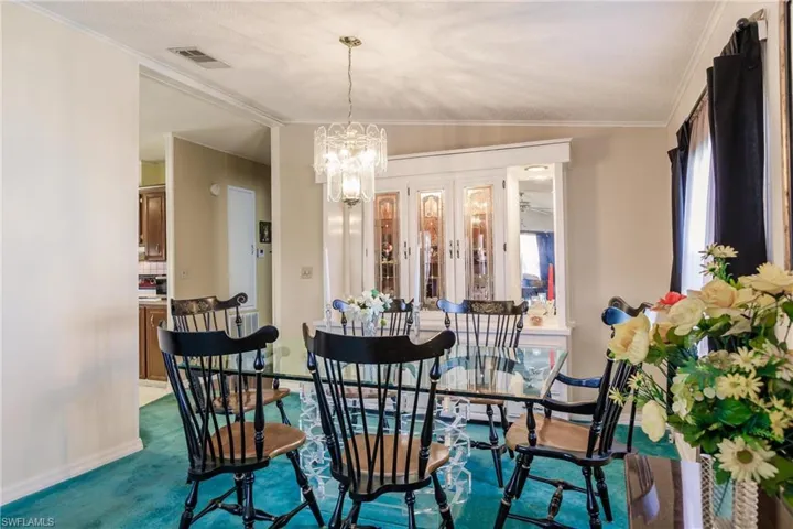 Dining room with carpet, ornamental molding, lofted ceiling, and a chandelier