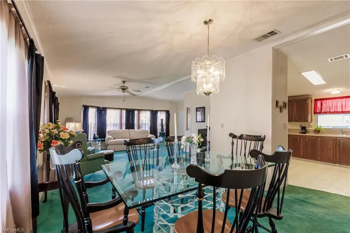 Dining space featuring carpet, a textured ceiling, vaulted ceiling, and ceiling fan with notable chandelier