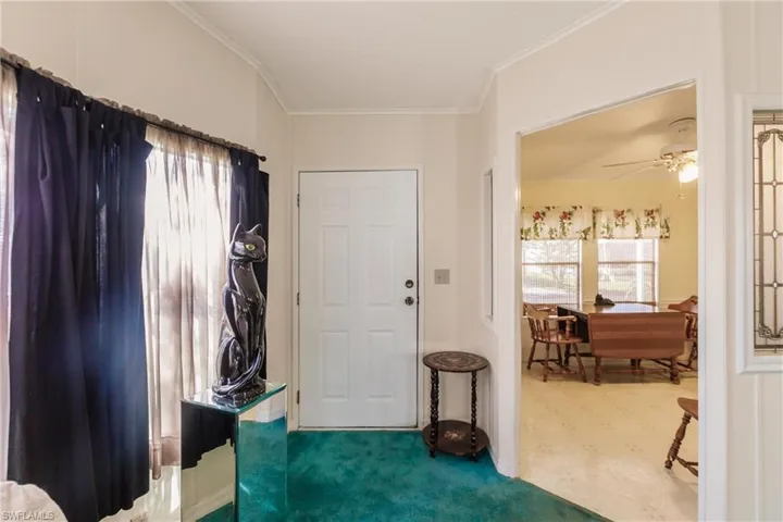 Foyer entrance with crown molding, carpet, and ceiling fan