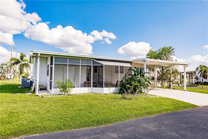 View of front of home with a front yard, a sunroom, and a carport