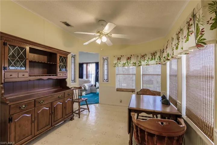 Dining room featuring ceiling fan, crown molding, and a textured ceiling