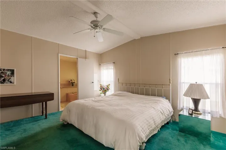 Bedroom with ceiling fan, lofted ceiling with beams, multiple windows, and carpet floors