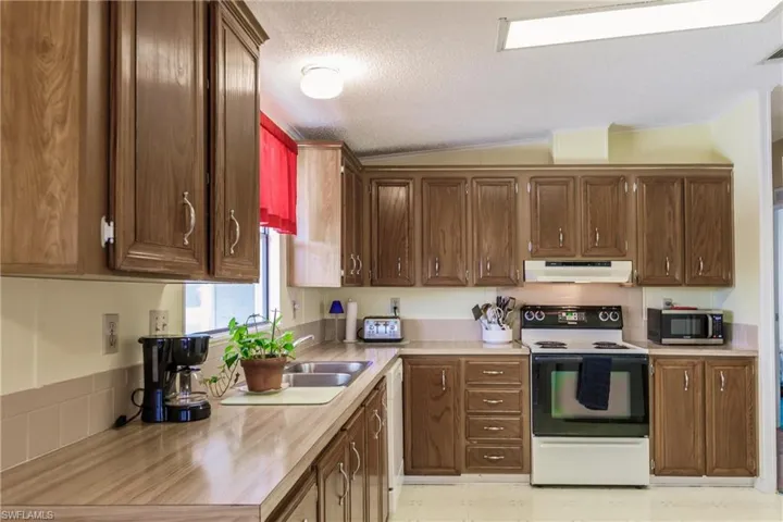 Kitchen featuring white appliances, butcher block countertops, a textured ceiling, and lofted ceiling