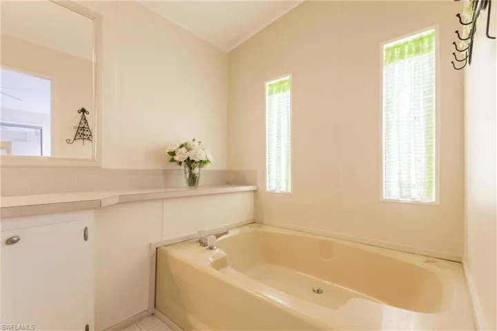 Bathroom with ornamental molding, a bath, and a wealth of natural light