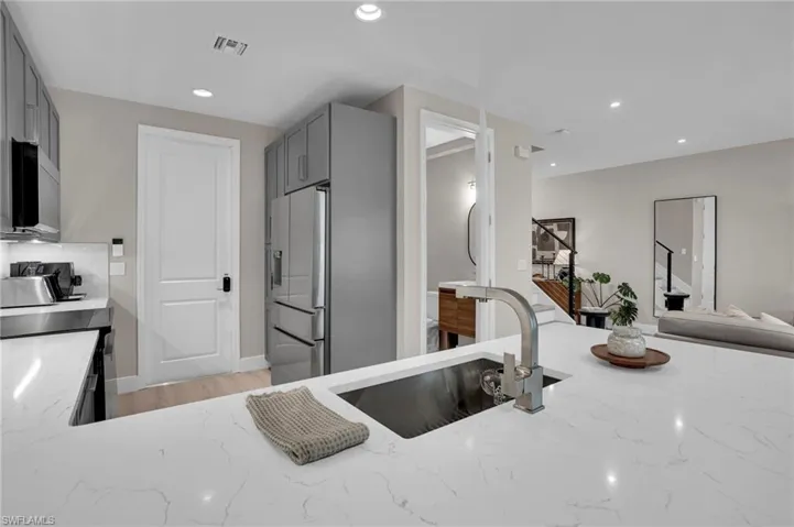 Kitchen featuring gray cabinets, light stone countertops, appliances with stainless steel finishes, recessed lighting, and light wood finished floors