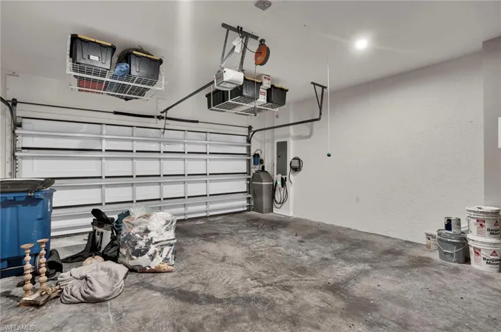 Garage with a textured wall, electric panel, and a garage door opener