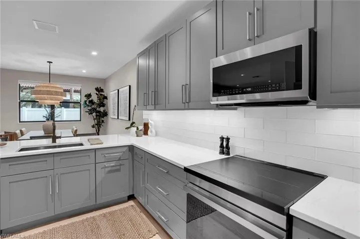 Kitchen with gray cabinets, stainless steel appliances, tasteful backsplash, recessed lighting, and a peninsula