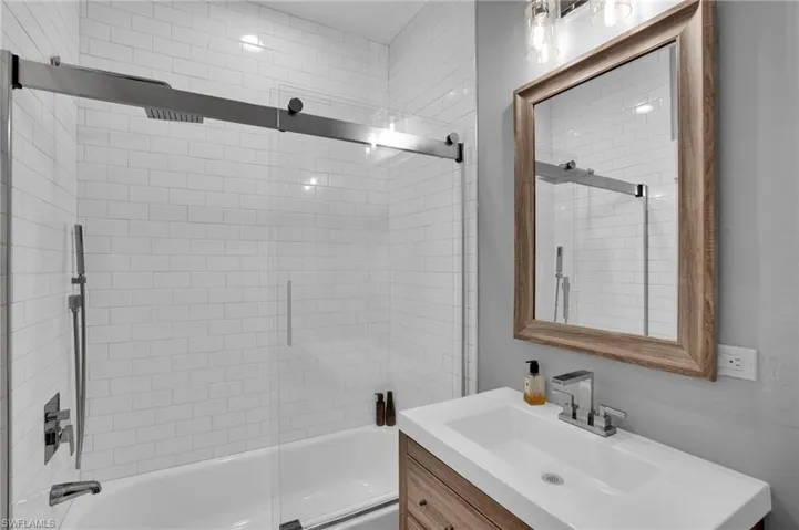 Bathroom with vanity and combined bath / shower with glass door