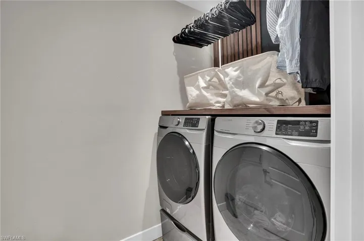 Washroom featuring independent washer and dryer and baseboards