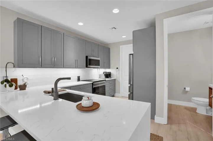 Kitchen featuring decorative backsplash, gray cabinetry, recessed lighting, a peninsula, and stainless steel appliances