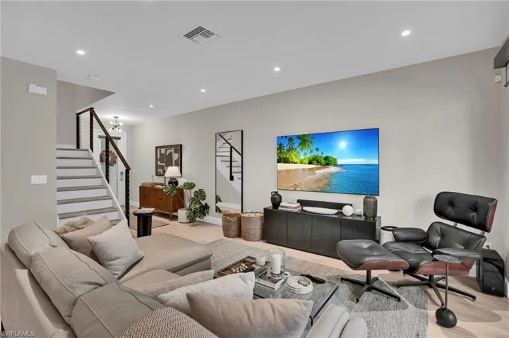 Living room with stairway, recessed lighting, and light wood finished floors