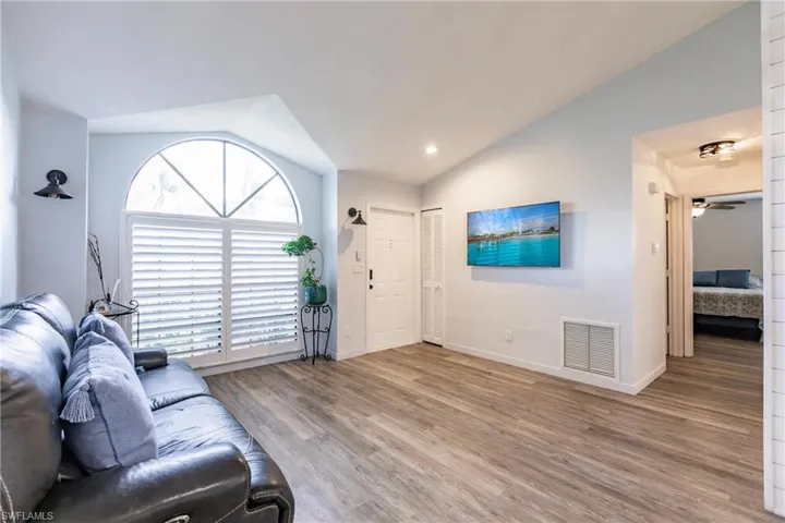 Living room with lofted ceiling, hardwood / wood-style flooring, and ceiling fan
