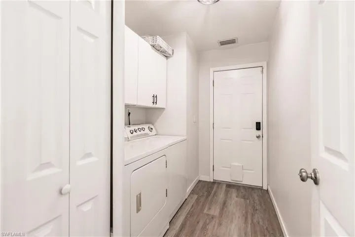 Laundry room with cabinets, light hardwood / wood-style flooring, and washing machine and clothes dryer