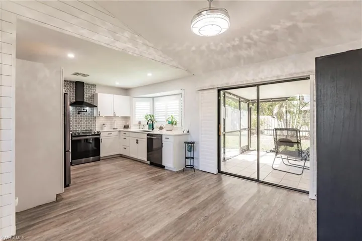 Kitchen featuring white cabinetry, stainless steel appliances, wall chimney exhaust hood, and light hardwood / wood-style flooring