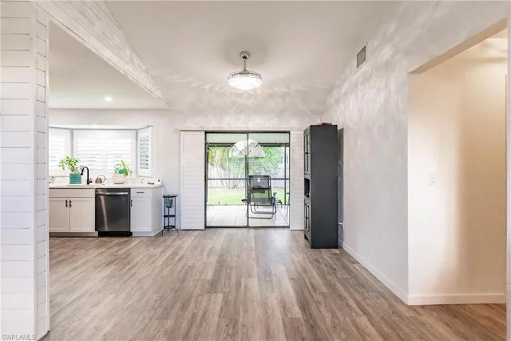 Kitchen with white cabinetry, light hardwood / wood-style floors, dishwasher, and a wealth of natural light