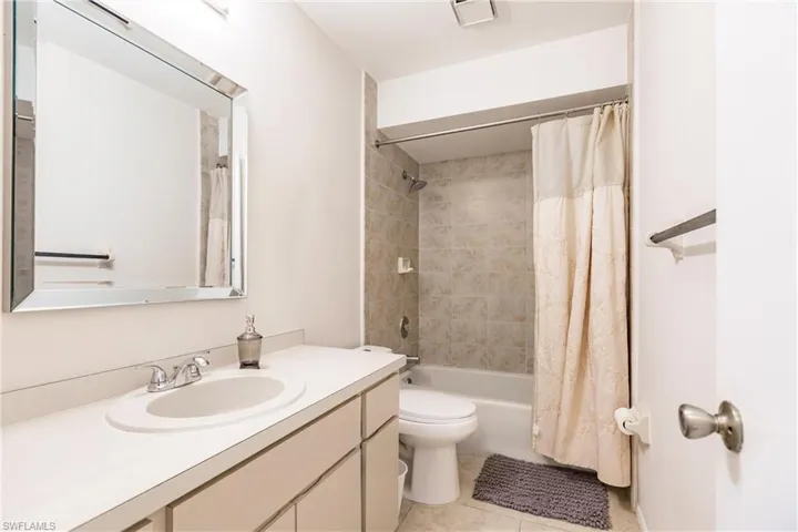 Full bathroom featuring vanity, shower / bath combination with curtain, toilet, and tile patterned floors