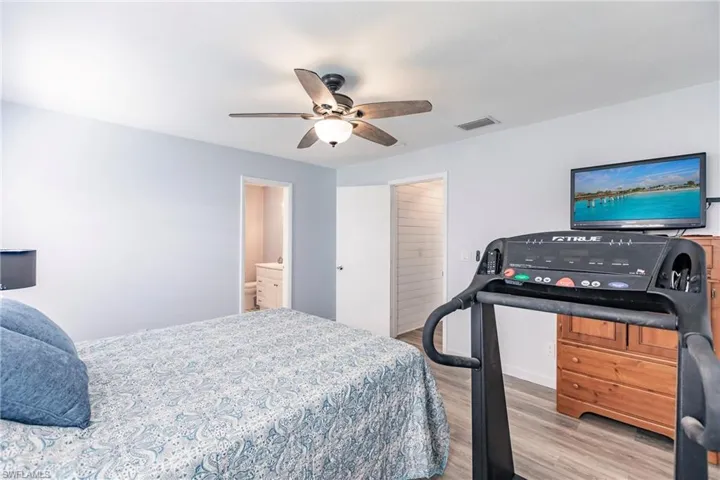 Bedroom with ensuite bathroom, wood-type flooring, and ceiling fan