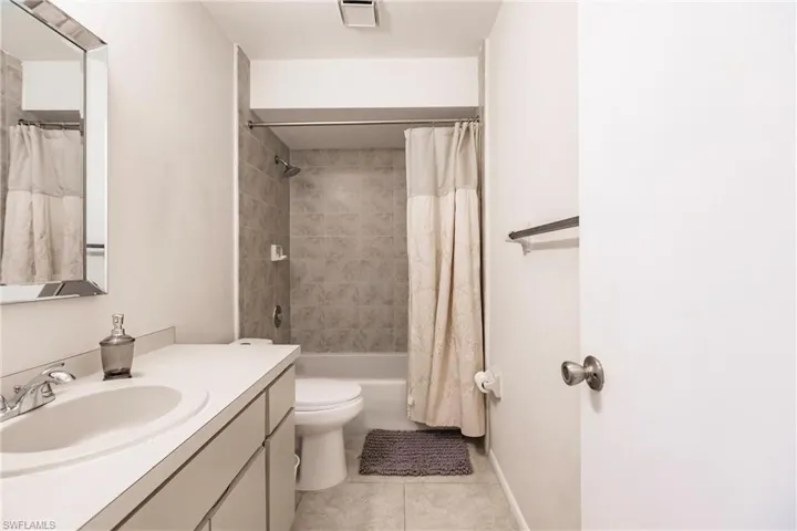 Full bathroom with vanity, shower / bath combo with shower curtain, toilet, and tile patterned flooring