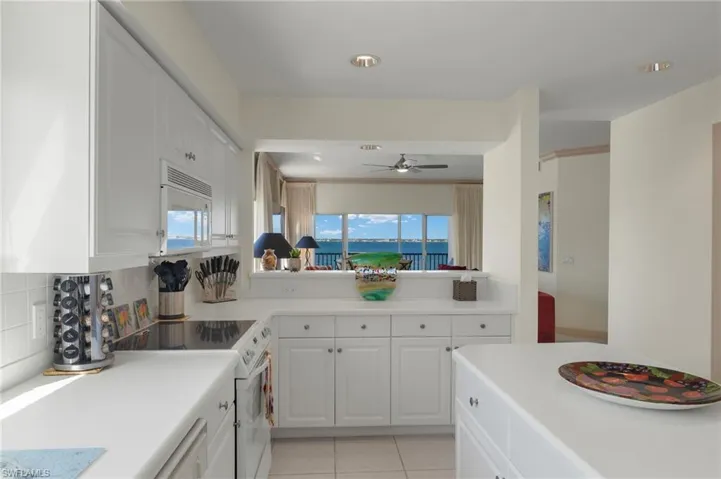 Kitchen featuring a wealth of natural light, white cabinets, white appliances, and decorative backsplash