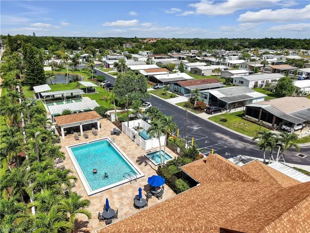 Community recreational area featuring a rectangular swimming pool, adjacent spa, covered patio, and shuffleboard courts
