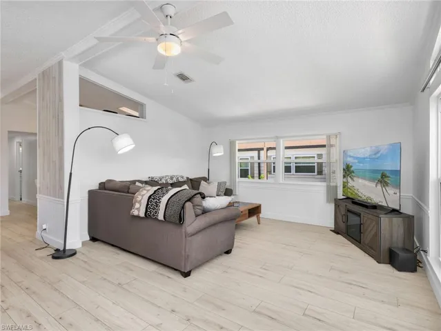 Open living area featuring wood-finish flooring, white walls, and a ceiling fan with integrated lighting