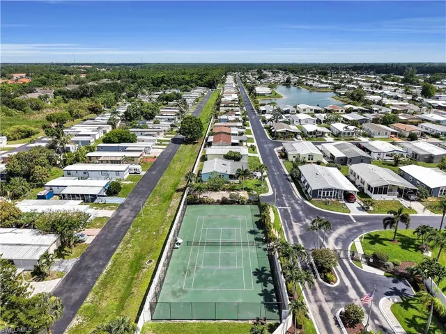 Aerial perspective showcasing a residential community with a tennis court