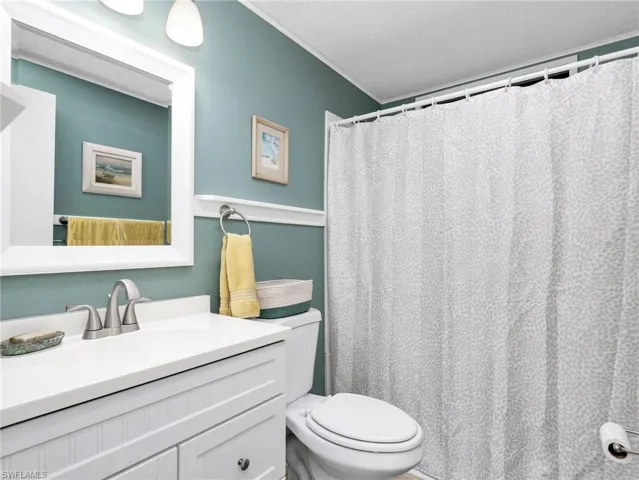 Bathroom featuring a white vanity with beadboard paneling, a white countertop, and a brushed nickel faucet