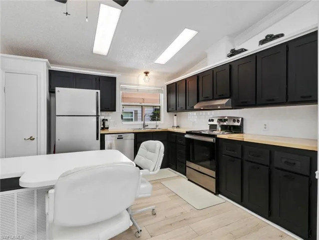 Contemporary kitchen featuring black cabinetry, light wood-finish countertops, and a white subway tile backsplash