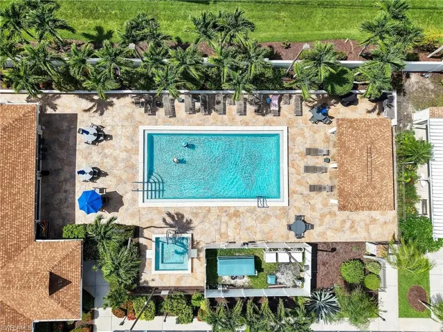 Community pool area featuring a rectangular swimming pool, an adjacent spa, and a surrounding paver deck
