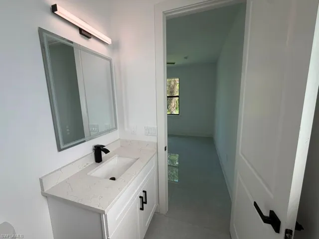 Bathroom vanity featuring a quartz-finish countertop, under-mount sink, and matte black faucet
