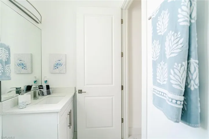 White vanity with shaker-style cabinetry, an integrated sink, and a light-toned countertop