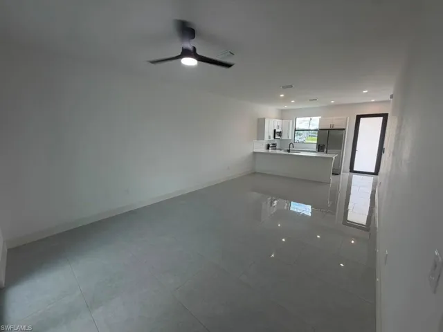Spacious open-concept living area featuring large format tile flooring and a modern ceiling fan