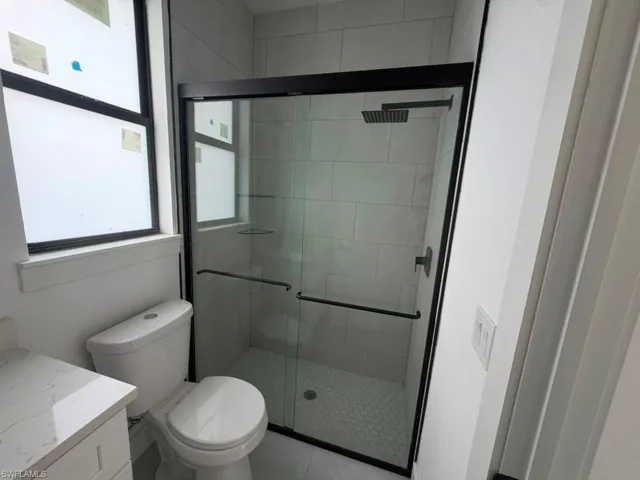 Modern bathroom featuring a glass-enclosed shower with matte black hardware, rectangular rain shower head, and hexagonal tile flooring