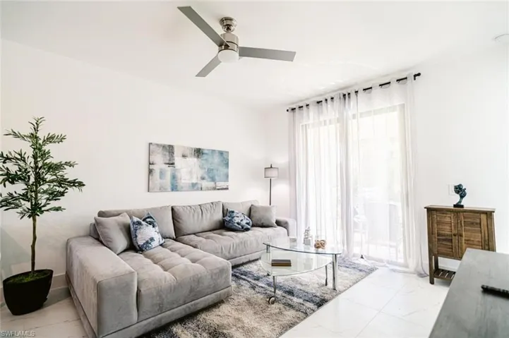 Bright living space featuring large-format tile flooring and a ceiling fan