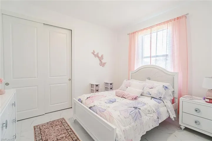 Room featuring white walls, white panel sliding closet doors, a window, and light-toned flooring