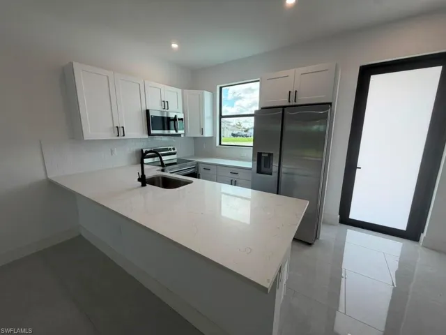 Modern kitchen featuring white shaker cabinetry, stainless steel appliances, a white subway tile backsplash, and light-toned countertops