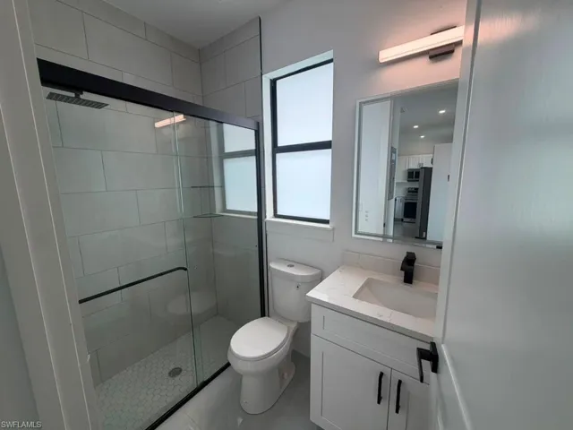 Modern bathroom featuring a glass-enclosed shower with black trim, a wall-mounted showerhead, and hexagonal floor tiling
