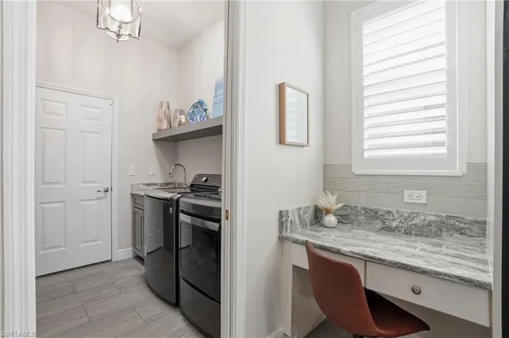 Washroom with wood finish floors, washing machine and clothes dryer, and an office area