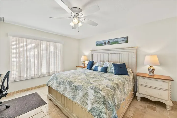 Bedroom featuring baseboards, visible vents, ceiling fan, and stone tile floors