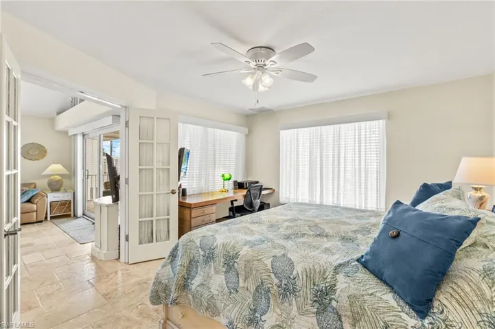 Bedroom featuring ceiling fan, french doors, and stone finish floor