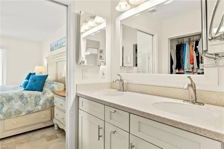 Ensuite bathroom featuring double vanity, a sink, visible vents, and stone tile floors