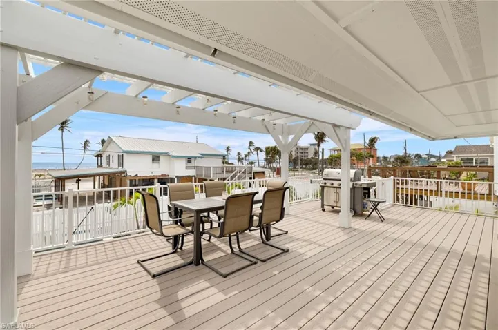 Wooden terrace with outdoor dining space, grilling area, and a pergola