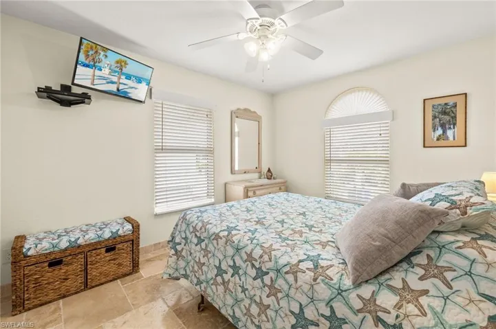 Bedroom featuring stone tile floors, baseboards, and a ceiling fan