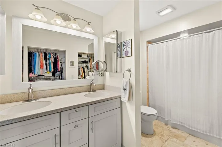 Full bathroom featuring a shower with shower curtain, a sink, toilet, and double vanity